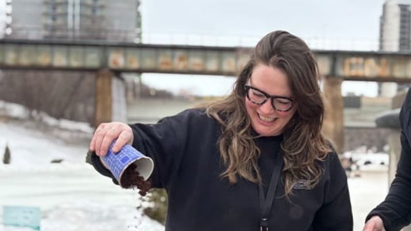 A woman pouring a cup of compost.